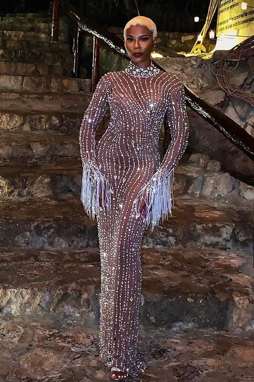 Yembi Fashion nude illusion crystal gown with sheer brown mesh, vertical wavy silver rhinestone patterns, and hanging crystal fringe cuffs