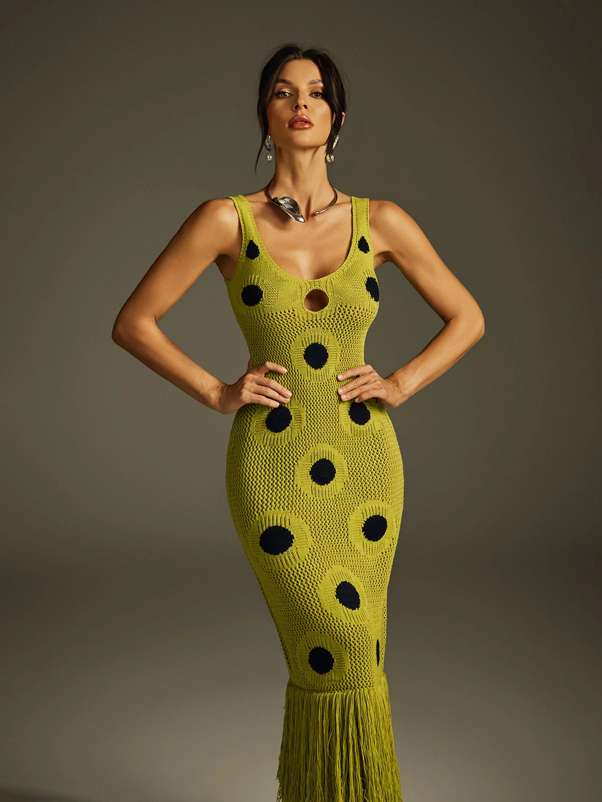 Yembi Fashion luxury olive green polka dot knit maxi dress featuring a chartreuse crochet sleeveless silhouette with black polka dots, center cutout, and a long fringe hem