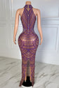 Mannequin wearing a purple and gold patterned dress on a marble floor with a plant in the background.