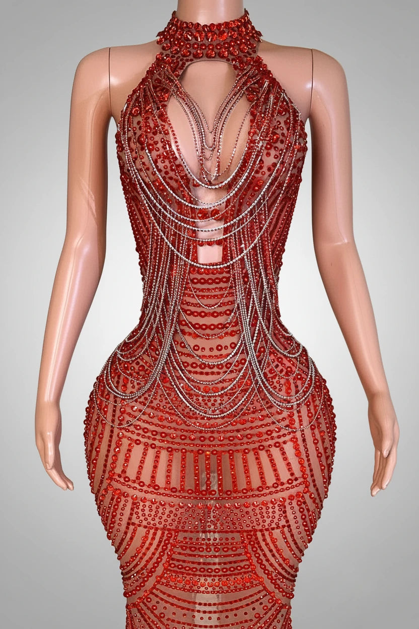 Red beaded dress on a mannequin against a decorative wall.