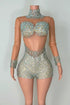 Yembi Fashion luxury silver rhinestone romper featuring a high-density crystal bustier and high-waisted sparkly shorts layout on a nude illusion sheer mesh long sleeve bodysuit