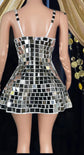 Woman wearing a shimmering mirror dress reflecting light, standing in a festival-like setting.